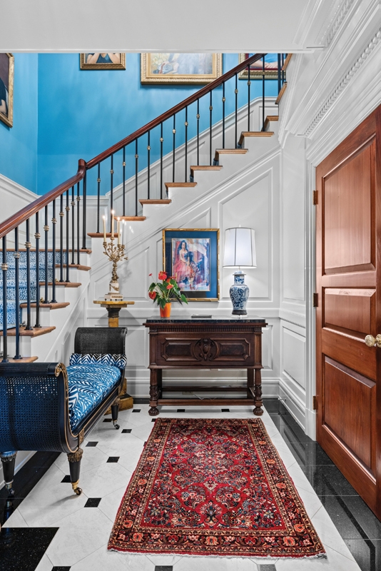 The entrance hall is painted a mid blue shade in a matte finish to accentuate the rich moldings done in a high gloss lacquer.