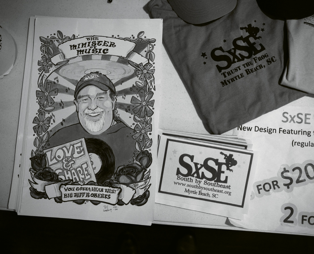 SXSE swag for sale during the Randall Bramblett show. Pictured is a poster of the late Jeff Roberts, nicknamed “The Minister of Music” by his close friends. Roberts was one of the founders of the series and his memory is honored with a toast before each show.