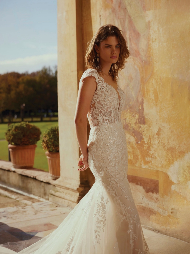 Demetrios - This fit and flare gown showcaes a deep V-neckline and appliques on the shoulders. The design extends into a scoop illusion keyhole with button closure on this style 1274 dress. Two Oaks Bridal Boutique, $2,480