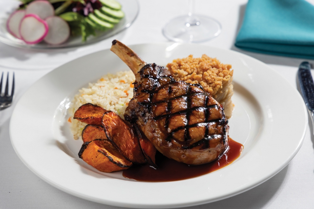 Grilled bone-in pork chop with herbed rice and an apple cider reduction