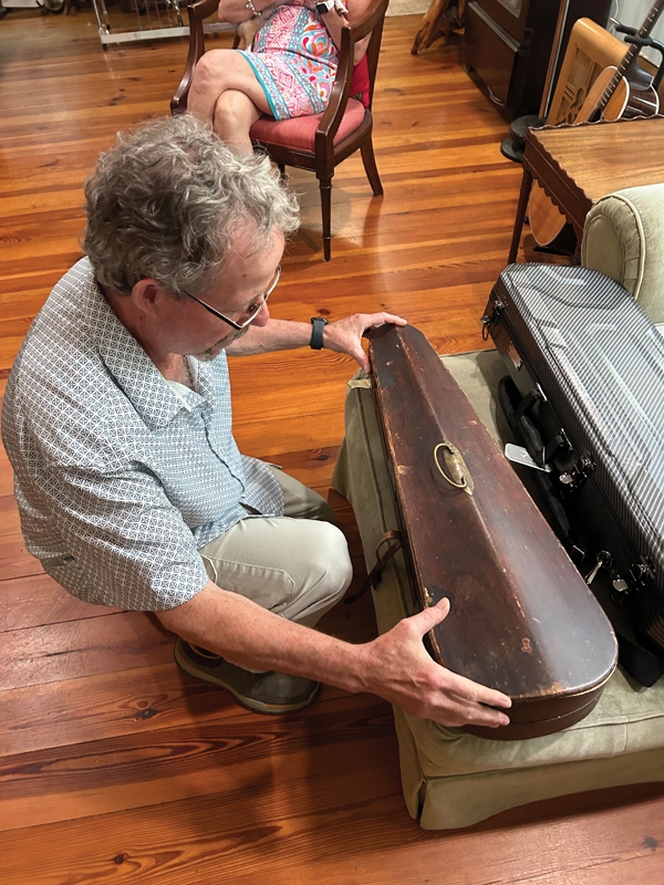 At his home in Pawleys Island, Dean Black holds the original “coffin” case of his great-grandfather’s 200-year-old violin. He traveled through Europe to Poland with the violin protected by the adjacent carbon fiber case.