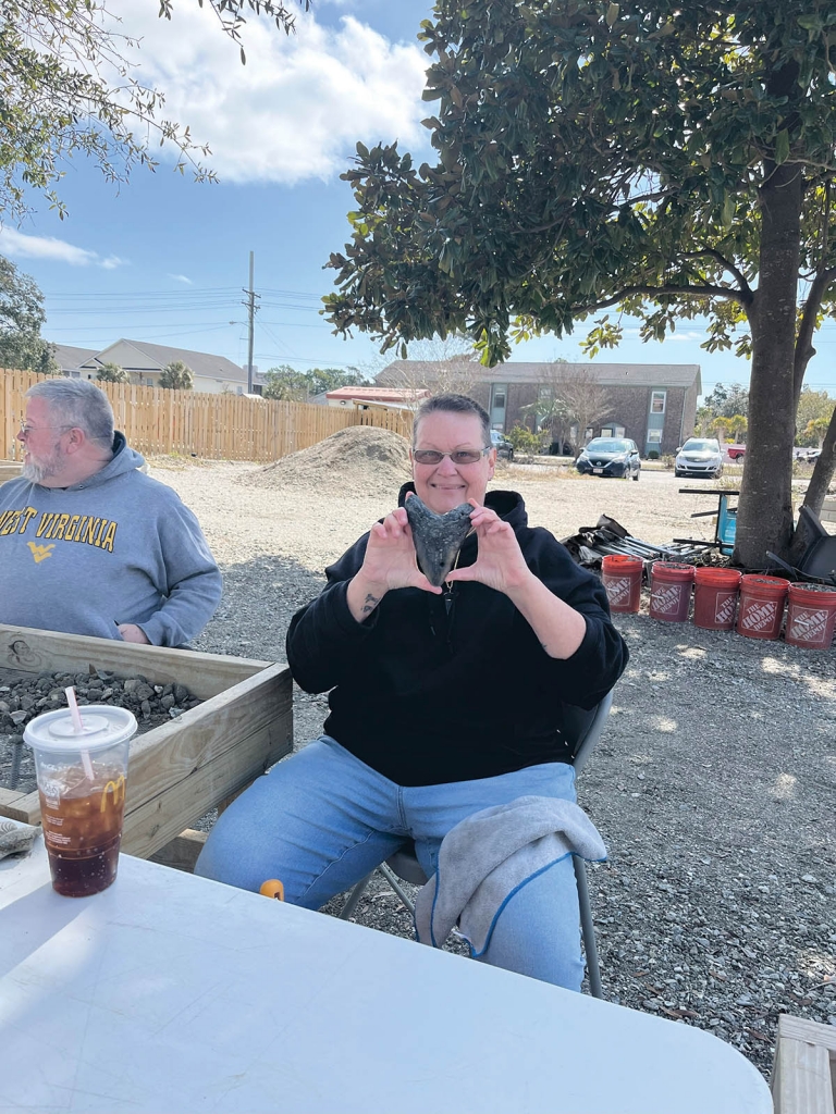 A customer holds a megalodon tooth, which Lauren Booth of Myrtle Beach Shark Tooth Adventures says is the biggest she has seen come out of a Megalodon Premium Bucket.