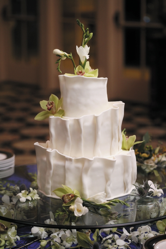 The Cake: Incredible Edibles’ Myra Ranta took inspiration for this cake from the unusual ruffling on the bodice, which was the bride’s favorite part of the dress. The cake was frosted in buttercream, then a hand-ruffled fondant was carefully applied to the sides.