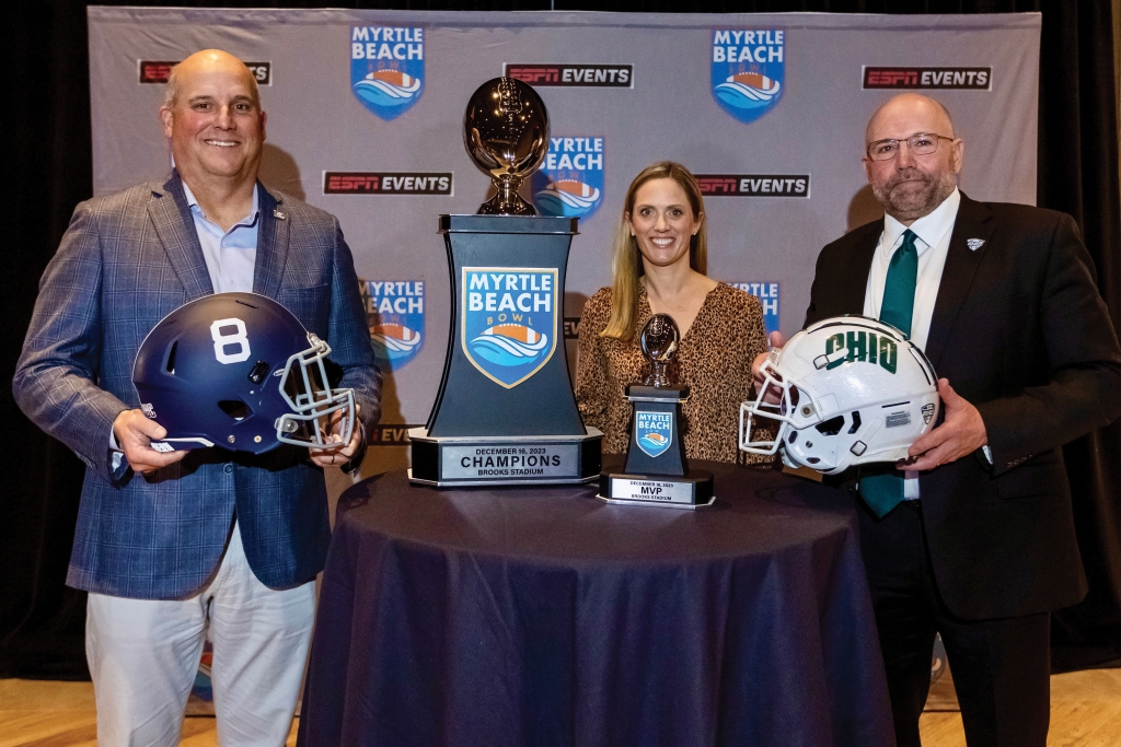 Rachel stands in between Georgia Southern head coach Clay Helton (left) and Ohio University head coach Tim Albin, the matchup at the 2023 Myrtle Beach Bowl.