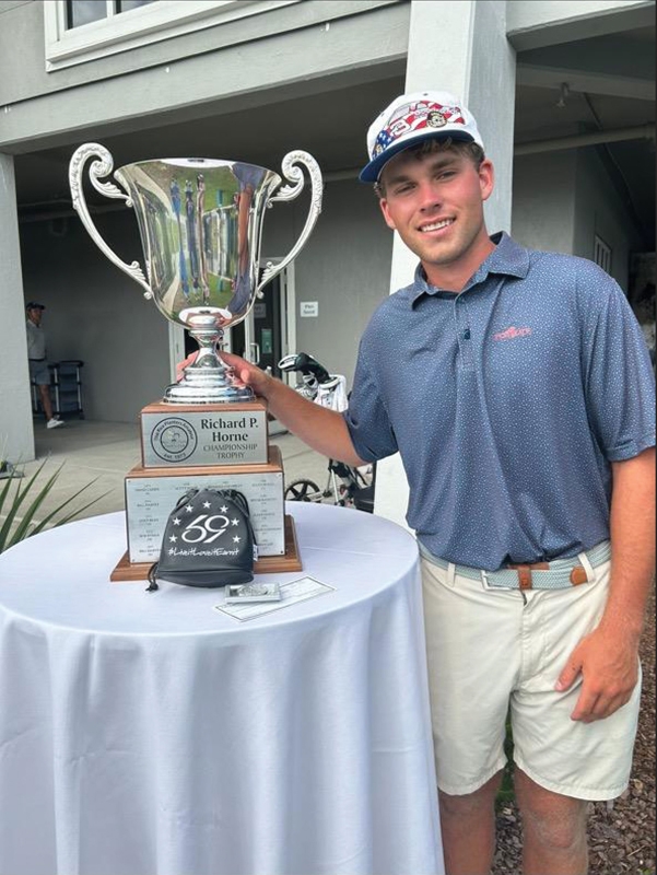 Cooper proudly stands with one of his many junior golf trophies.