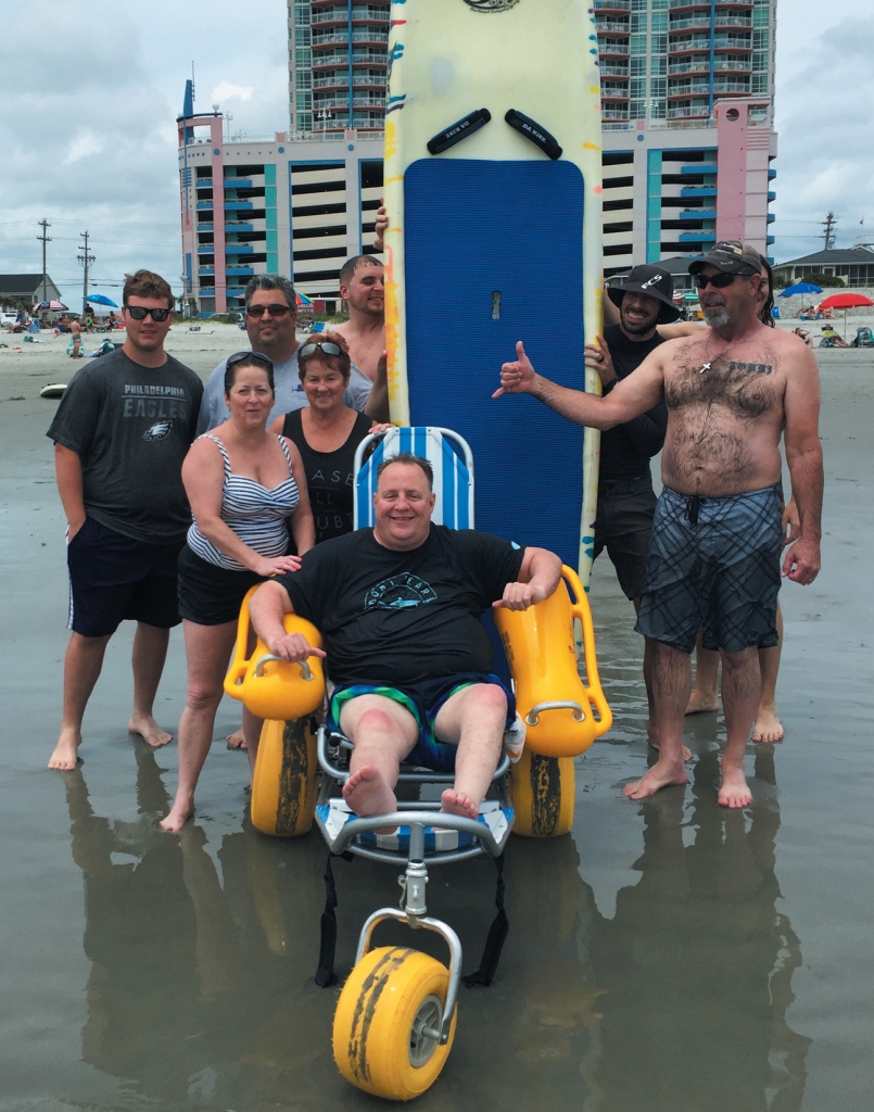 Tracy Price poses with relatives and volunteers with Wheel to Surf after they took him surfing in Cherry Grove in May—the first time Price had been in the ocean since he became dependent on a wheelchair after an ATV accident in 2004.