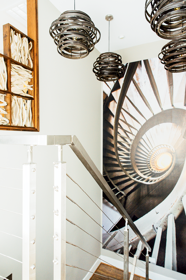 The stunning floating stairway features a wall photo from the inside of a lighthouse and bentwood light fixtures.