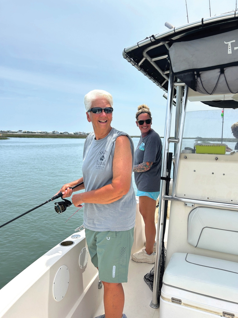 Customer Debbie Helms and Captain Coble watch with all smiles as others aboard catch fish.