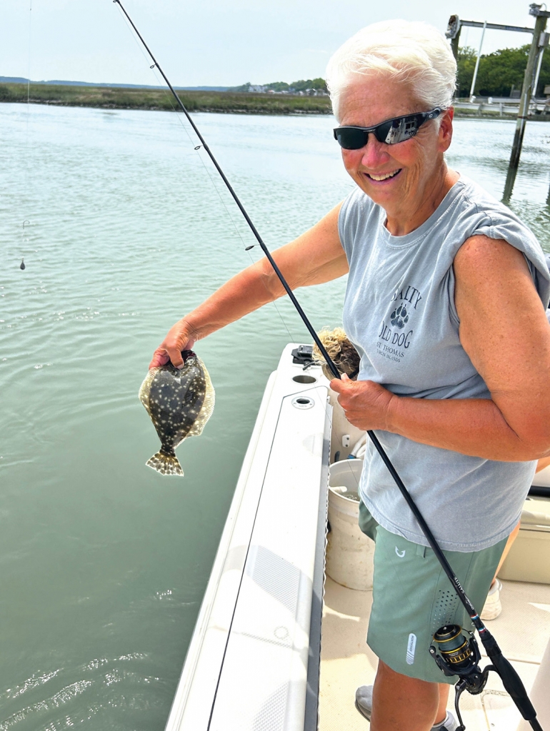Charter customer Debbie Helms is all smiles with her first flounder of the day, though it&#039;s undersized and will be released.